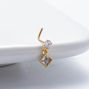 L-shaped gold nose stud with clear round and square zircon pendant on white tray