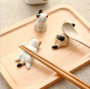Japanese style ceramic cat chopstick rests with hand-painted patterns on a wooden tray