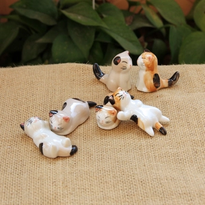 Detailed view of six unique hand-painted ceramic cat chopstick rests on a burlap surface