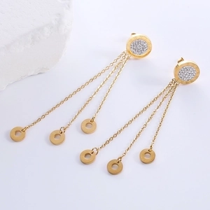 Detail of gold fringe earrings with Roman numeral engraving and sparkling crystal accents