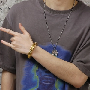Close-up of a golden dragon scale bracelet on wrist with a retro street style look