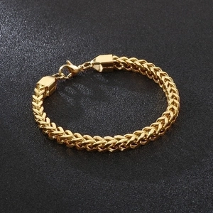 Polished gold stainless steel Franco link bracelet with lobster clasp on dark background