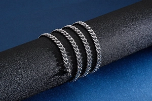 Detail of silver Cuban link steel chain wrapped on a black textured cylinder display stand