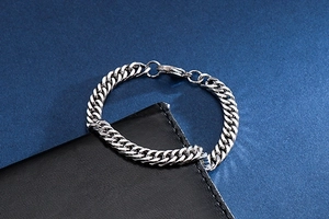 Close-up of silver stainless steel Cuban link chain bracelet on black leather wallet