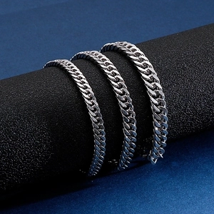 Three widths of silver stainless steel Cuban link bracelets on a black display stand