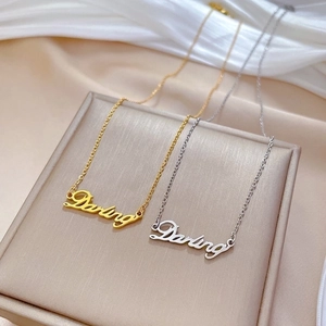 Gold and silver Darling script necklaces on silk background, minimalist titanium steel jewelry