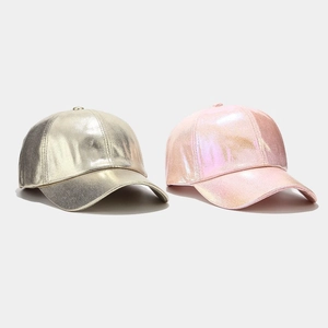 Metallic gold and iridescent pink baseball caps with crinkled PU texture in a studio shot