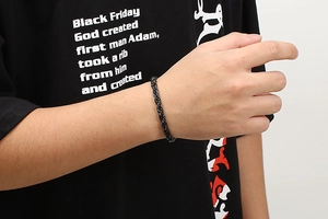Dettaglio del bracciale a catena a corda intrecciata nera da 6 mm indossato da un uomo