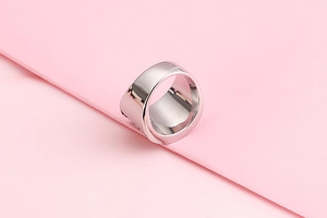 Close-up of a wide polished 304 stainless steel band ring on a pink background
