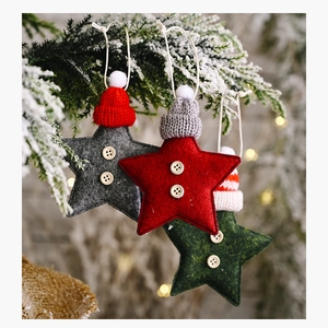 Close-up of star ornaments with knitted hats on snowy pine branches for Christmas