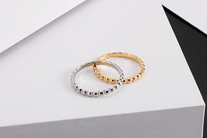 Detailed view of polished gold and silver beaded stacking rings on minimalist display