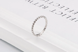 Detail of silver beaded ring with high-polished finish on a minimalist display stand