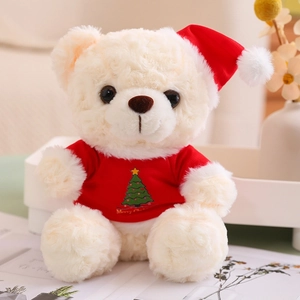Close-up of a cream teddy bear wearing a red Christmas tree sweater and festive hat