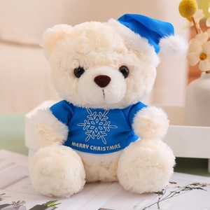 Close-up of a white plush teddy bear wearing a blue snowflake Christmas hat and t-shirt