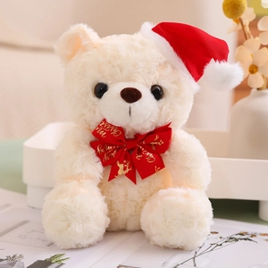 Detailed close-up of a cream teddy bear wearing a red Christmas hat and Merry Christmas bow