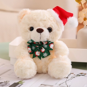 Detail of a plush cream teddy bear wearing a red Christmas hat and green holiday bowtie