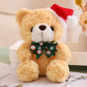 Close-up of a brown teddy bear wearing a red Christmas hat and green festive bowtie