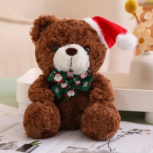 Detail of a brown teddy bear with a red Santa hat and green bow in a cozy indoor setting