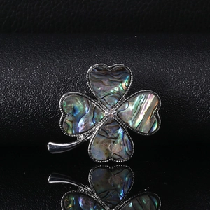 Macro shot of silver clover brooch with natural abalone shell and rhinestone inlay