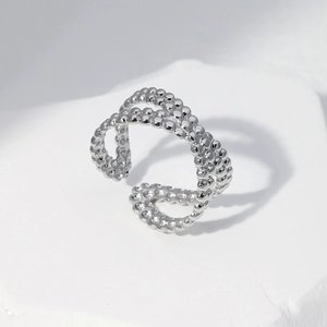 Detail shot of a silver multi-layer beaded open ring on a white textured stone base