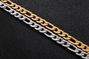 Macro detail showing the polished gold and silver Figaro link chains in stainless steel