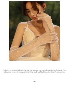 Close-up of elegant ivory bridal tulle gloves decorated with shimmering white pearls