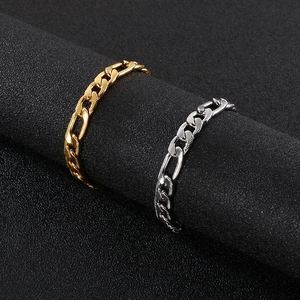 Polished gold and silver Figaro link rings displayed on a textured black stand