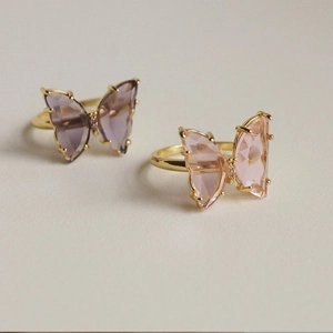 Detailed view of elegant gold-plated butterfly rings with pink and lavender crystals