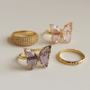 Detail of four-piece gold plated ring set with pink and purple crystal butterfly charms