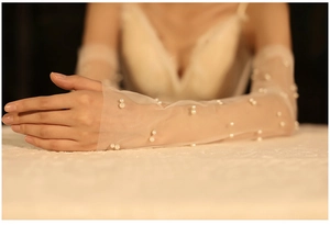 Close-up of elegant white mesh bridal sleeves with delicate pearl embellishments