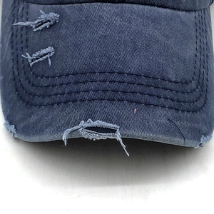 Macro view showing distressed details and frayed edges on washed navy denim baseball cap