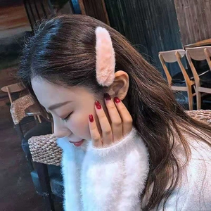 Side view of a soft pink plush hair clip worn by a model in a cozy cafe setting