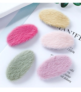 Flat lay of five colorful plush oval hair clips on a stylish magazine background