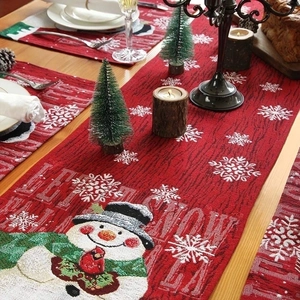 Detail of red Christmas table runner set with embroidered snowmen and festive patterns