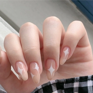 Nude almond press-on nails with white star patterns and glossy finish on a hand