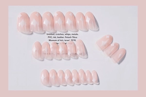 Detail of nude pink press-on nails featuring white minimalist star patterns and glossy finish