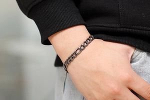 Close-up of gunmetal stainless steel Figaro chain bracelet showing the masculine links