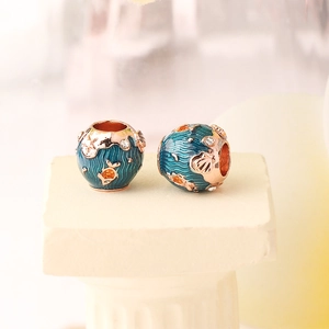 Macro detail of ocean charm featuring rose gold fish and blue enamel sea wave patterns