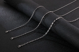 Detailed view of silver stainless steel box chains on a dark textured background