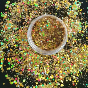 Golden holographic hexagonal glitter mix for nail art in transparent jar on black background