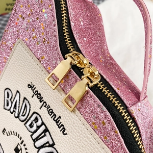 Detail of pink sequin handbag with white leather patch and gold double metal zippers