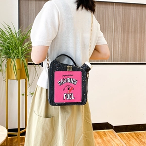 Detail of creative black oil drum bag with glitter letters worn by a model in a modern room