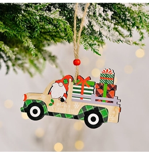 Detail of wooden Christmas truck ornament with Santa hanging on a snowy pine branch