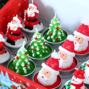 Detailed close-up of Santa and Christmas tree shaped candles in a festive red gift box