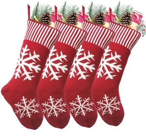 Detailed close-up of four red knitted Christmas stockings with white snowflake patterns