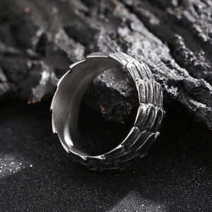 Macro shot of silver punk dragon scale texture ring on dark rugged volcanic stone