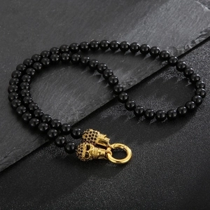 Men's punk titanium steel black bead bracelet featuring gold skull charms on slate background