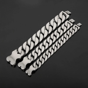 Detailed view of three polished silver Cuban link bracelets with bone-shaped clasps