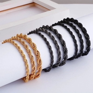 Classic gold and black twisted rope chain necklaces displayed on white cylinder stand