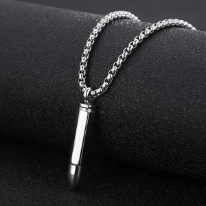 Macro shot of silver bullet pendant with box chain on a black textured background